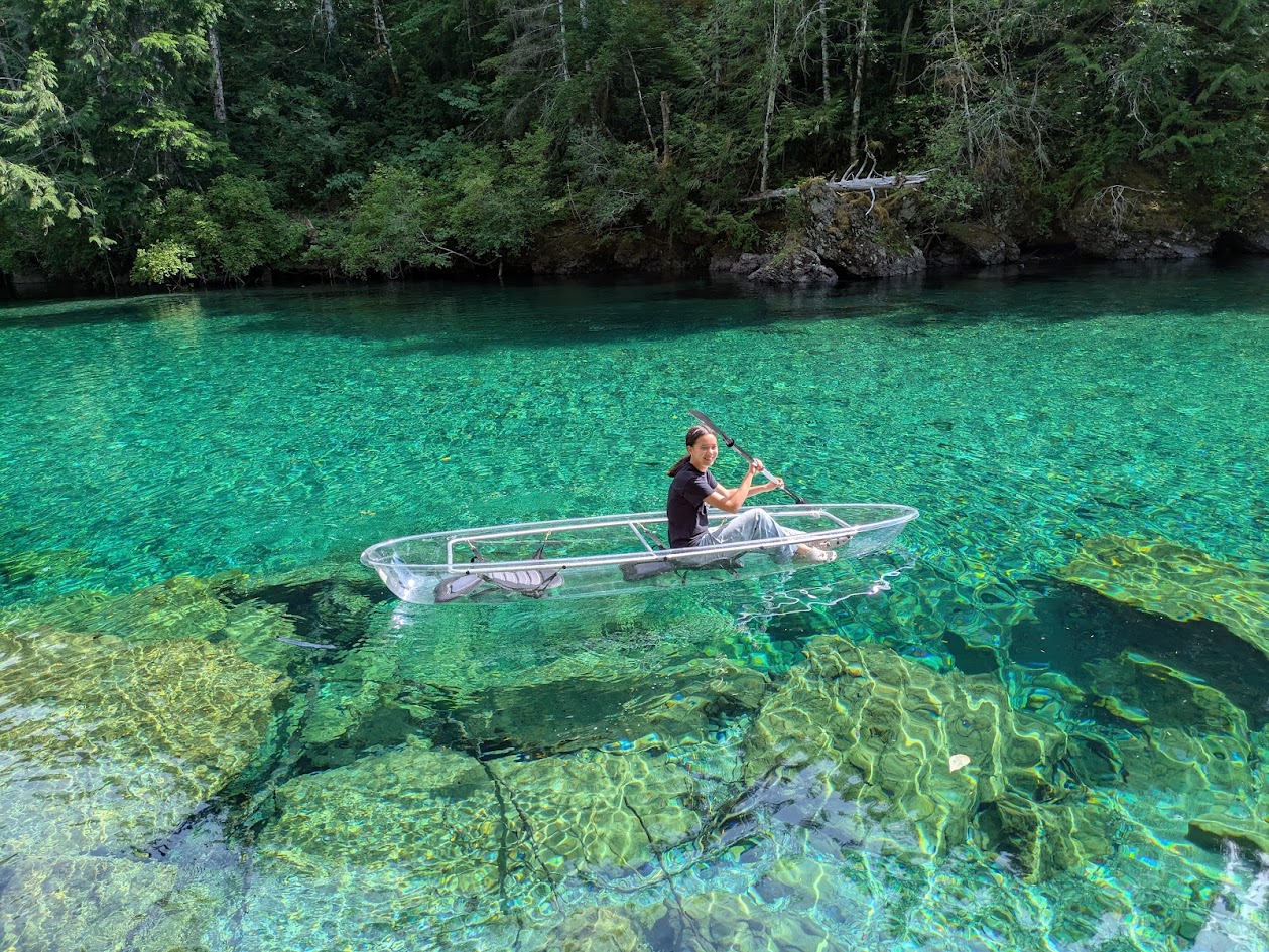 Rae paddling a clear kayak on turquoise water
